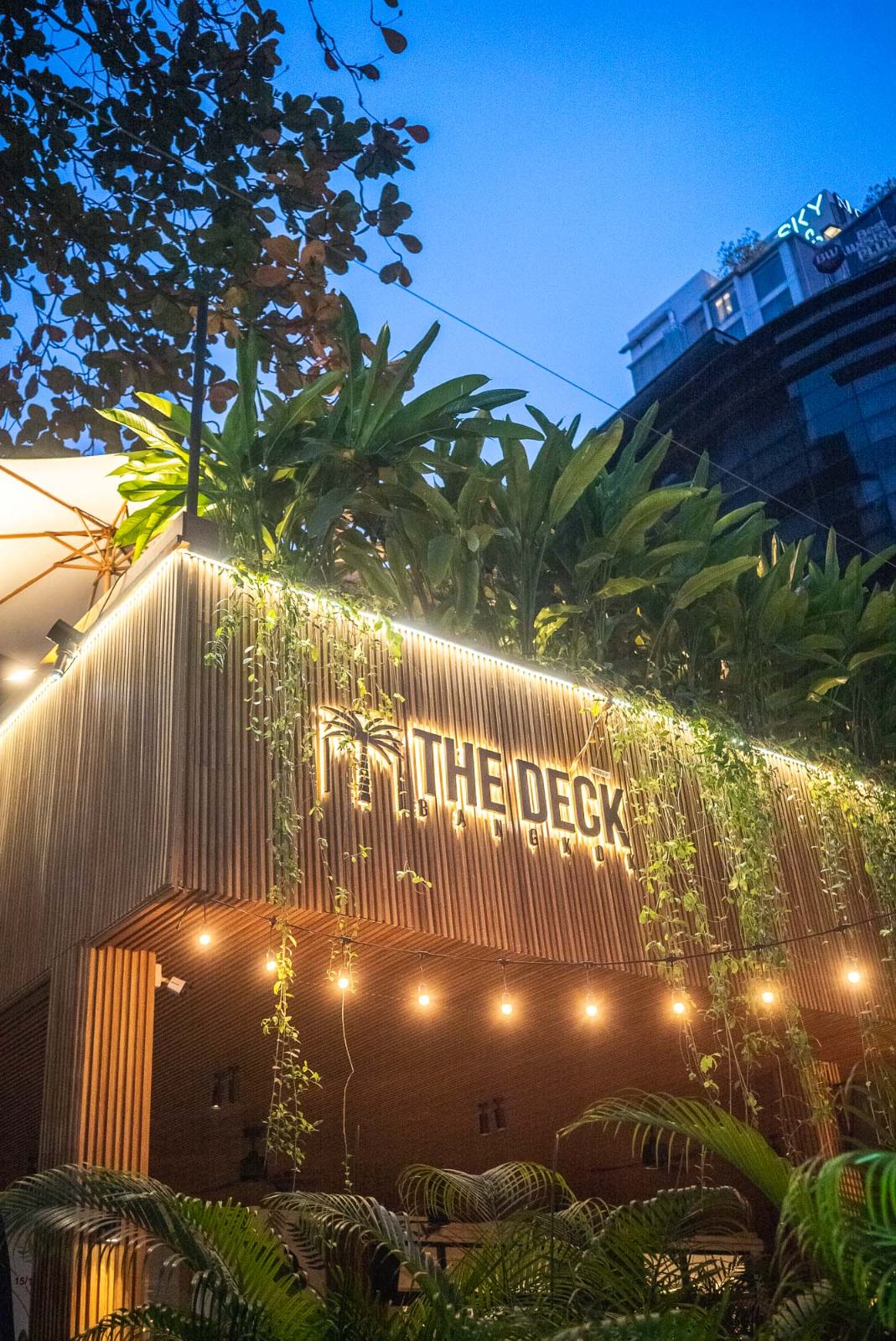 The Deck's garden terrace at night, tables lit under the trees